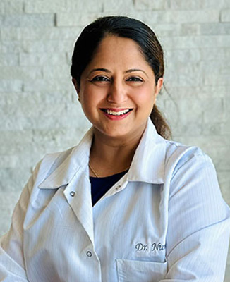 The image features a woman in a white lab coat, standing against a neutral background. She has a smile on her face and is looking directly at the camera.