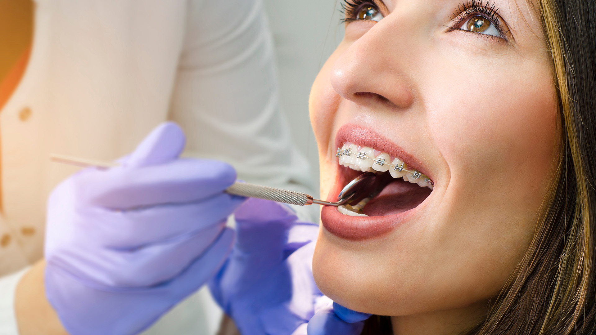 A woman receiving dental treatment, with a dental professional performing the procedure and a medical setting evident.