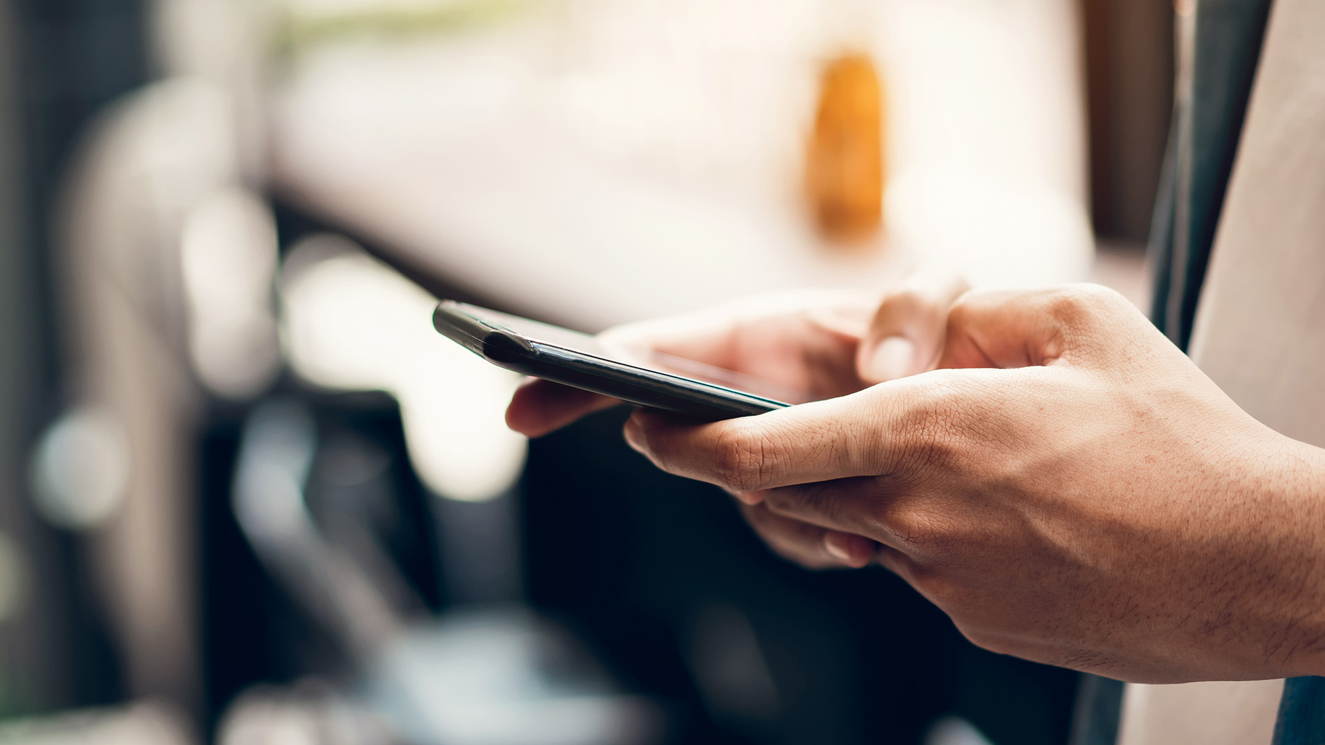 An individual using a smartphone, captured in a blurred background.