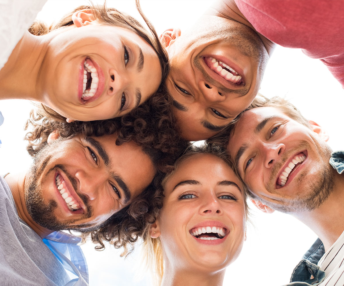 A group of young people, possibly friends or family members, are smiling and posing together for a photo with one person in the center. They appear to be happy and enjoying each other s company.