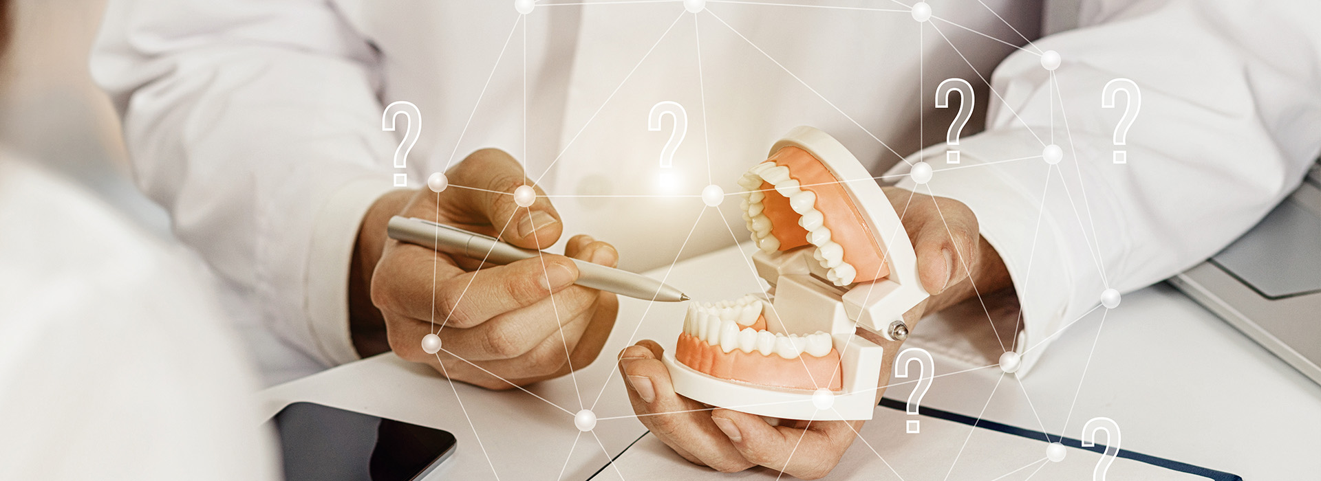 A dental professional examining a patient s teeth with a digital display showing a 3D model of the upper and lower jaw.