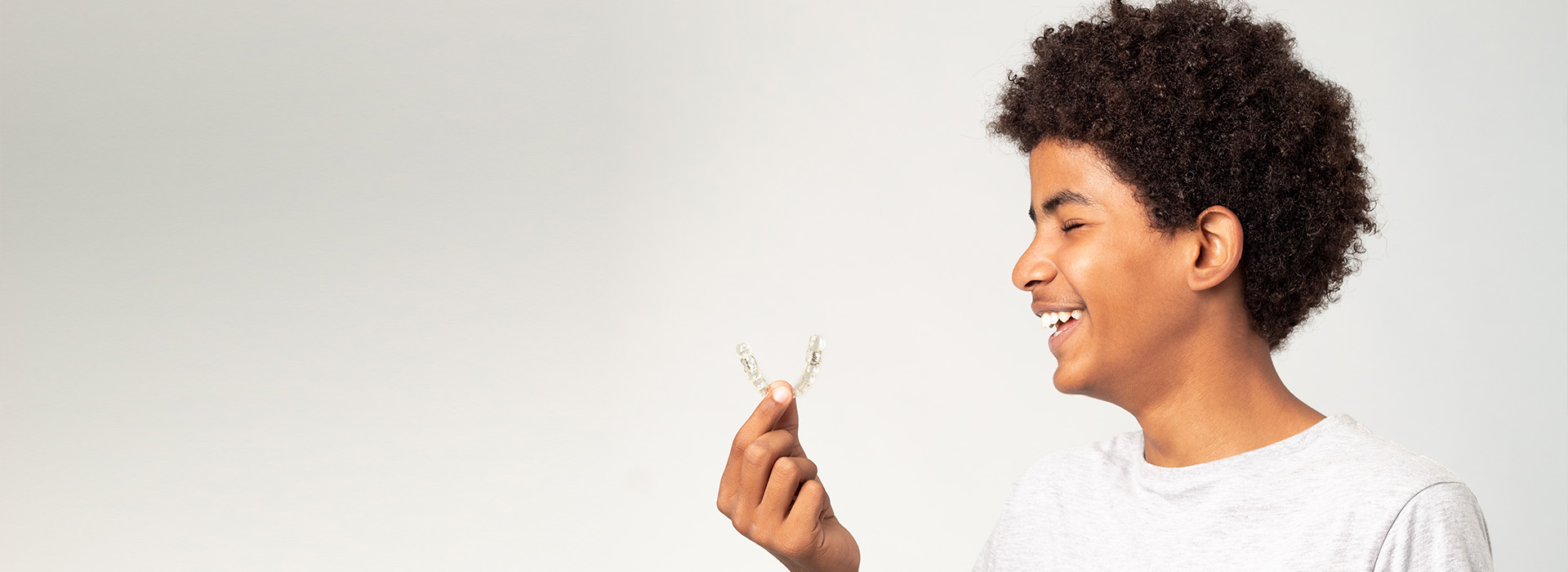 A young person holding a flower with a joyful expression, against a white background.