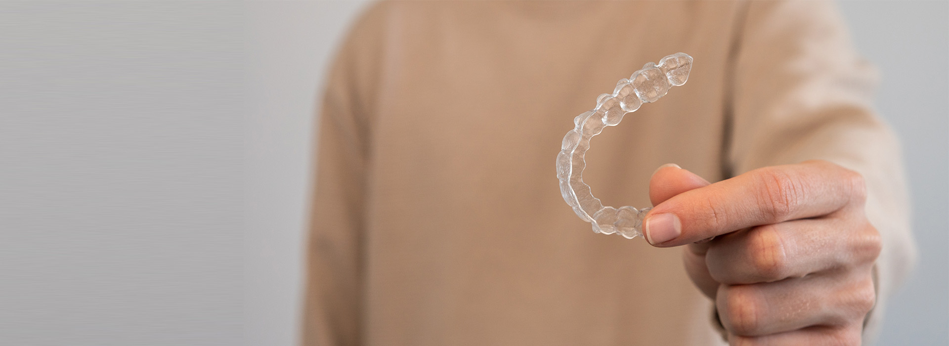 An individual s hand holding a transparent soap bubble against a blurred background.