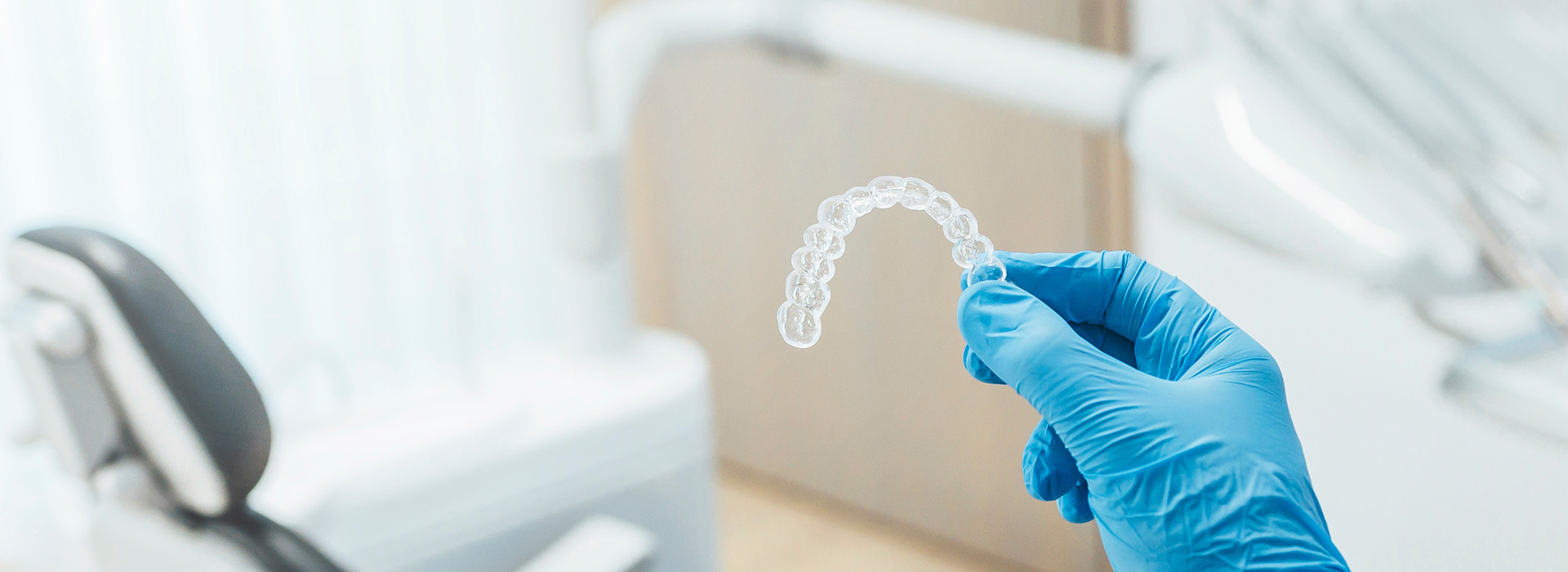 The image shows a hand wearing blue gloves holding a transparent dental impression material, with a focus on the material and the glove.