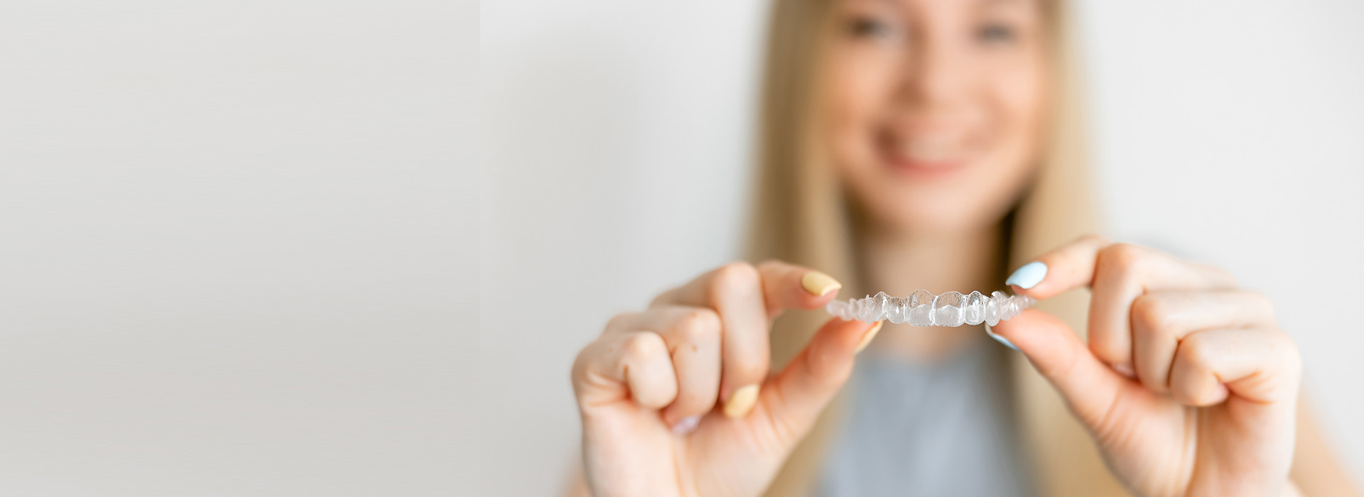 A woman is holding a small, clear object with her hands.