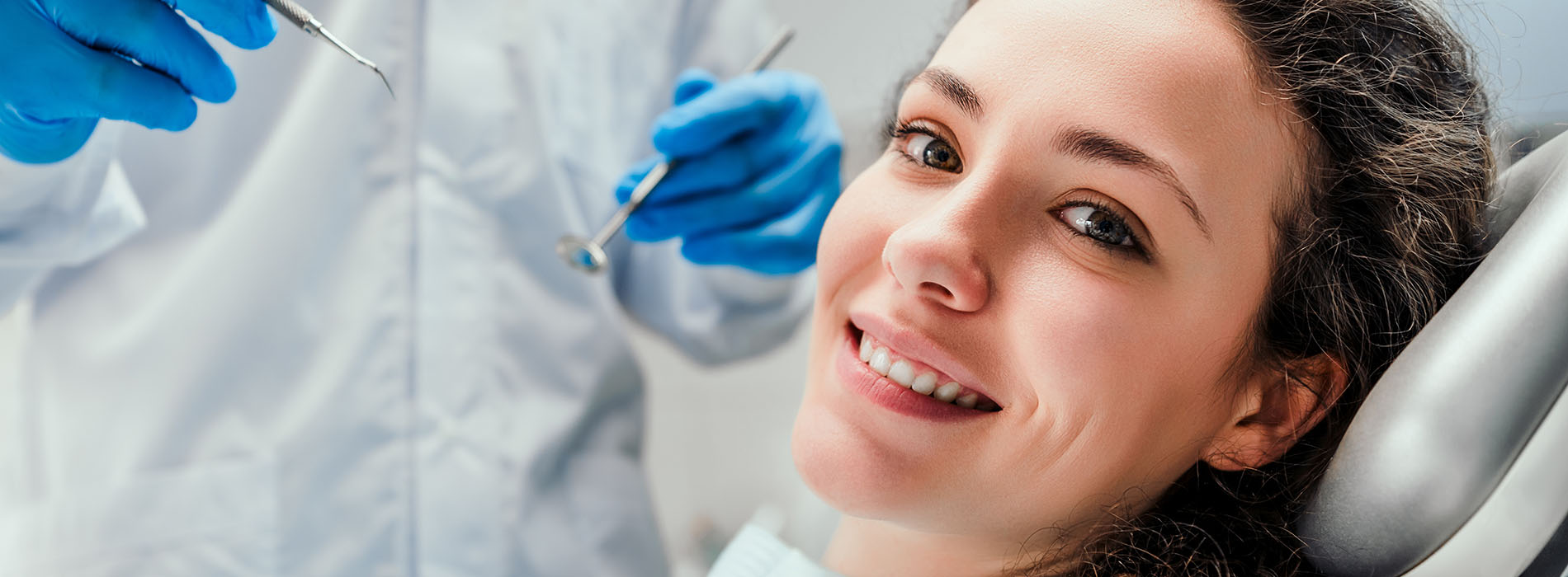 Woman receiving dental care in a professional setting, smiling with eyes closed.