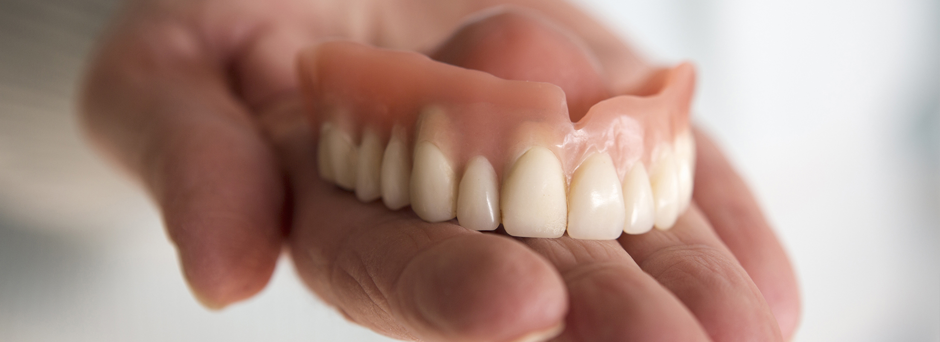 A person holding an artificial set of human teeth.