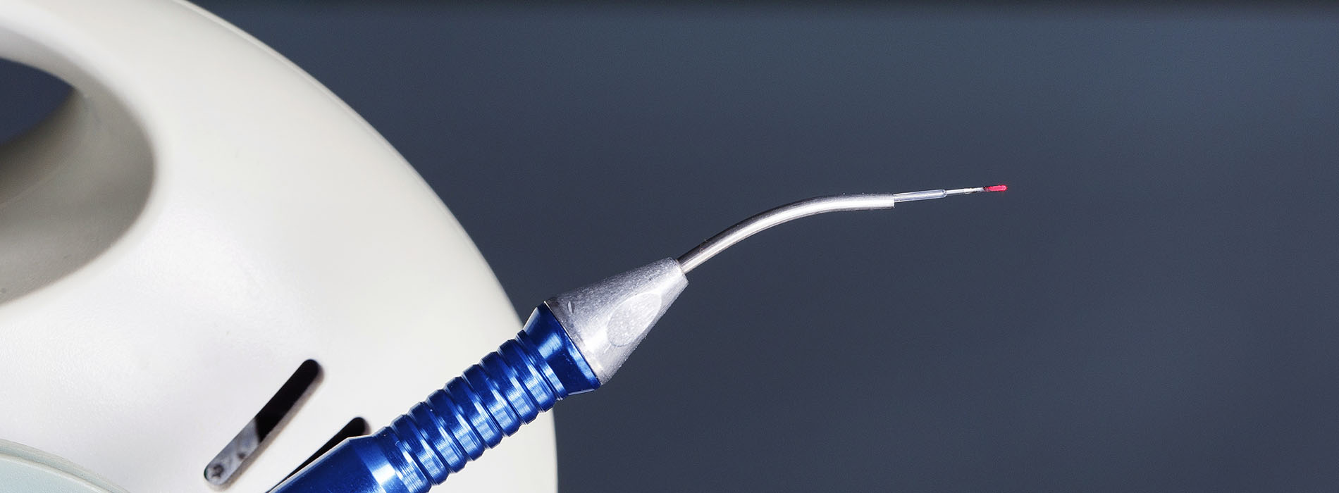 A medical device with a needle, set against a blurred background.