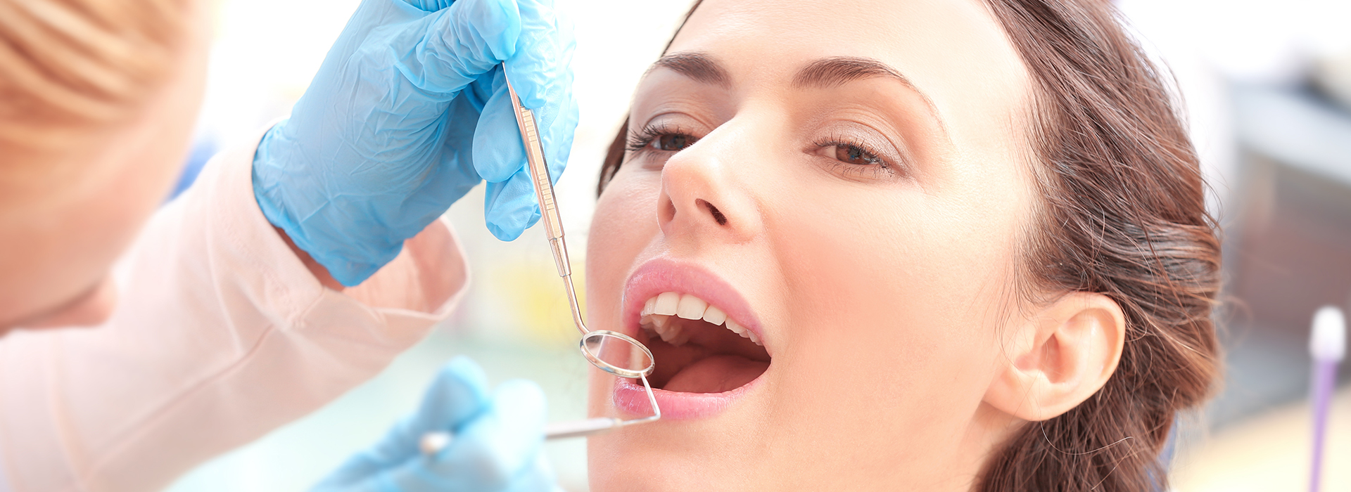 A woman receiving dental care, with a dentist using a drill on her teeth.