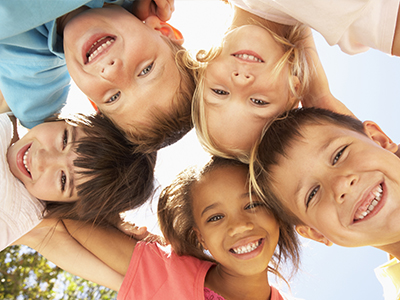 A group of children, possibly siblings, smiling and posing for a photo outdoors.