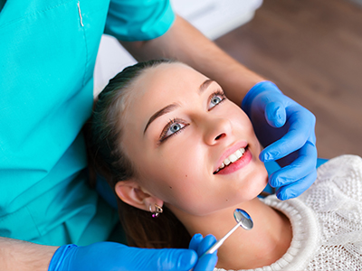 A dental professional is performing a smile enhancement procedure on a patient, with the focus on the dental chair and equipment.