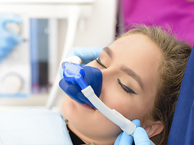 A woman receiving medical attention, with a blue oxygen mask covering her nose and mouth.